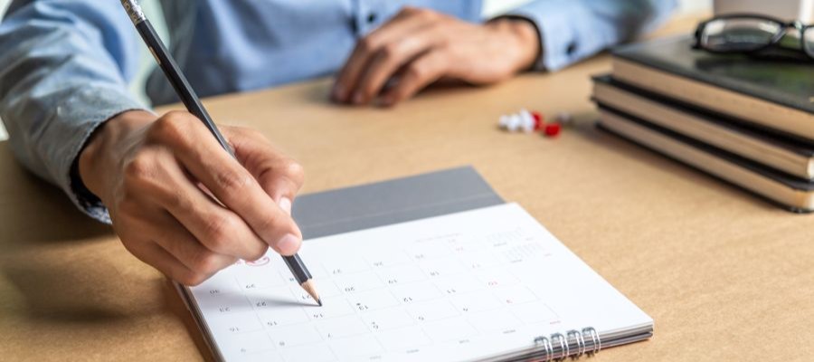 An image of someone holding a pencil on a calendar.