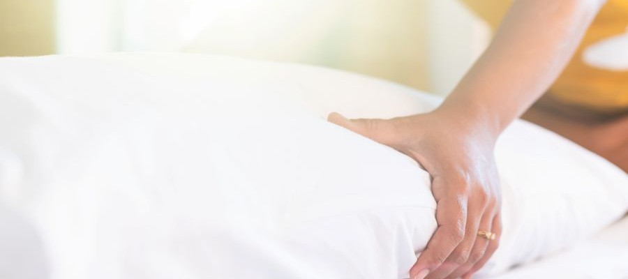 A person uses their hand to test out a new pillow.