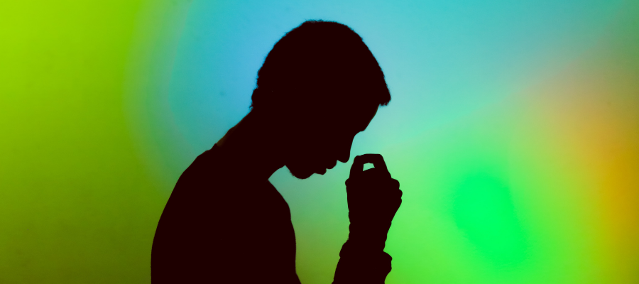 A male silhouette against a green and blue colored background.