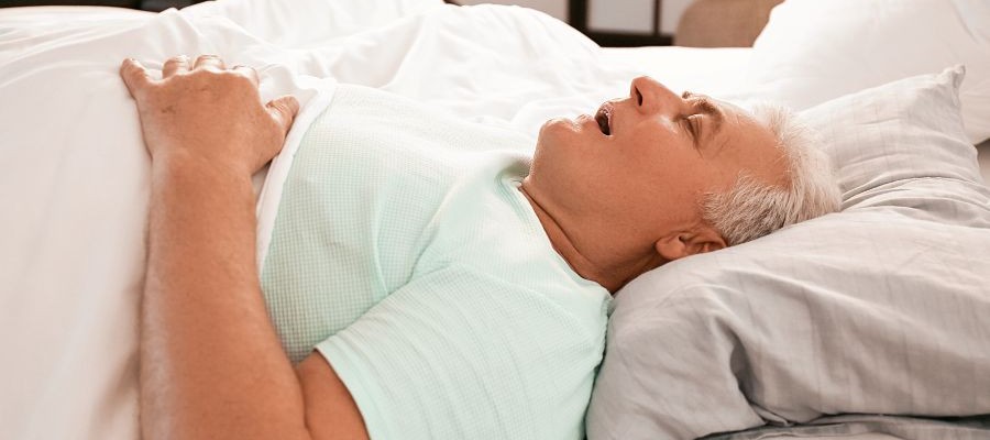 Older man asleep on his back with his mouth open.
