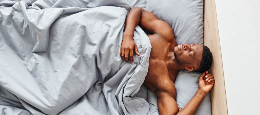 A young, black man take a nap in a bright room.