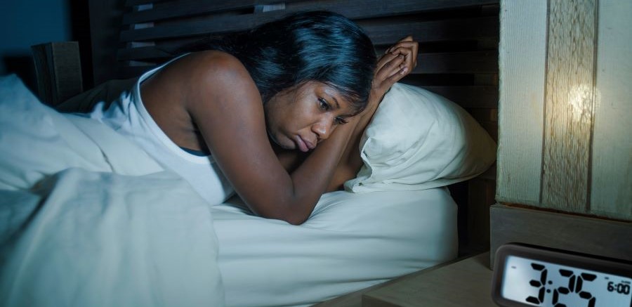 Woman in bed awake, with an alarm clock beside her that reads 3:25 AM.