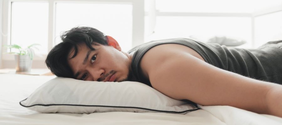 A man is on his stomach with his face turned to the side. He has a wide eyed but blank expression on his face.