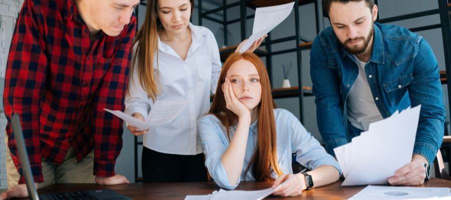 Overworked woman staring blankly while coworkers try to get her attention.