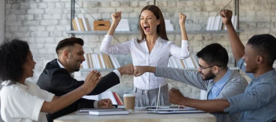 Group of happy coworkers celebrating with fist bumps, cheering.